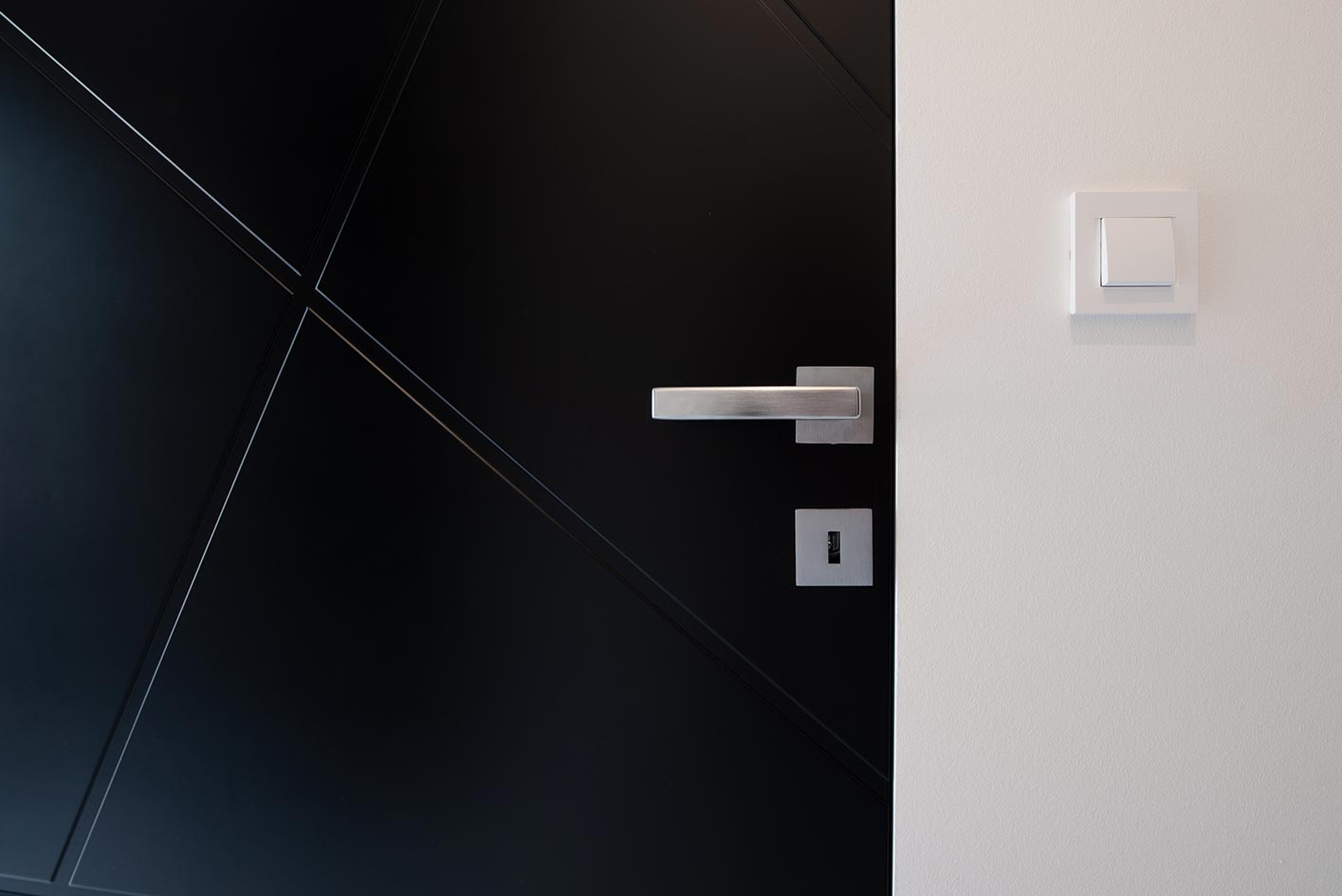 Detailaufnahme einer schwarzen Tür mit Edelstahlgriff