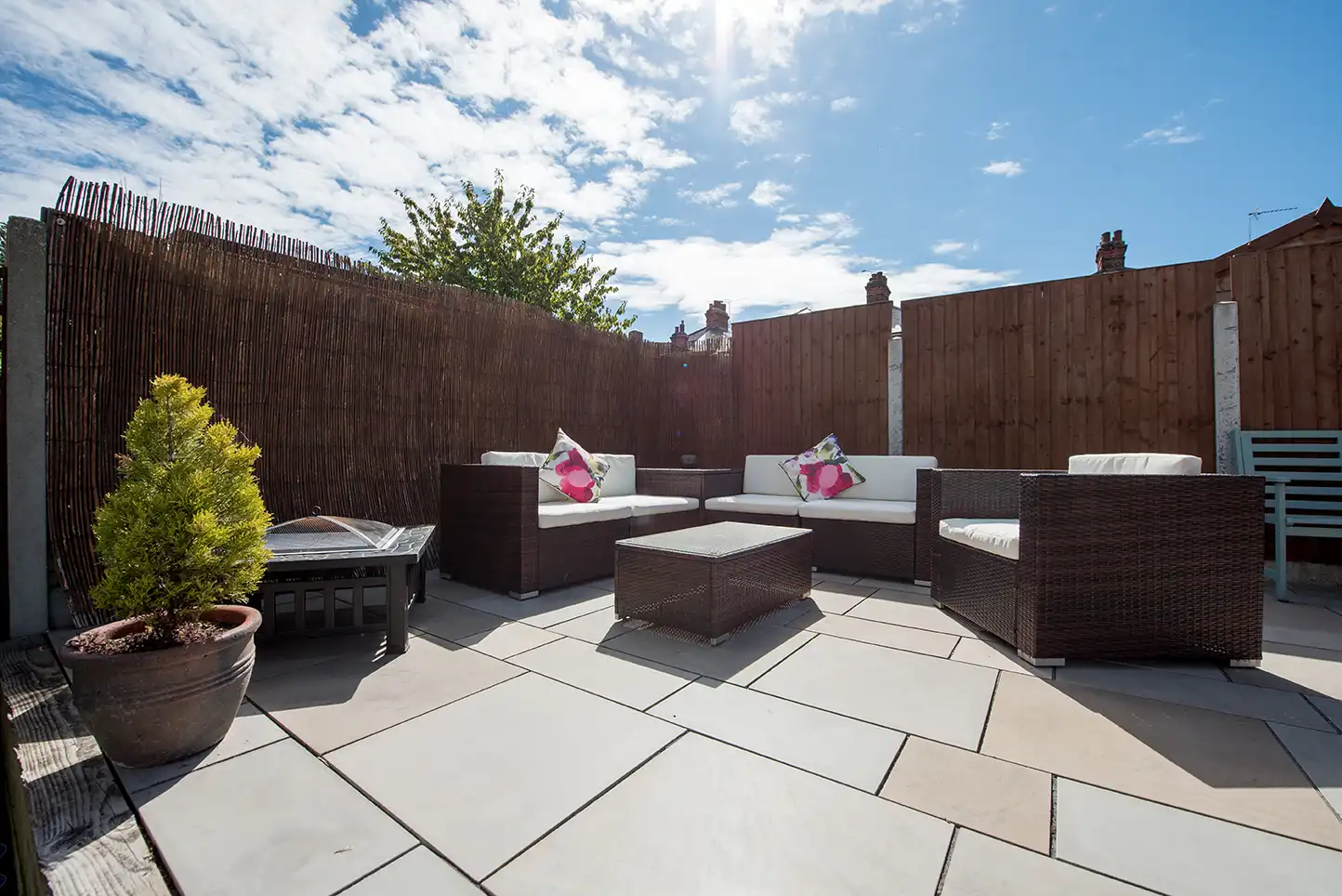 Große Terrasse mit hellem Bodenbelag und umlaufendem Holzsichtschutz
