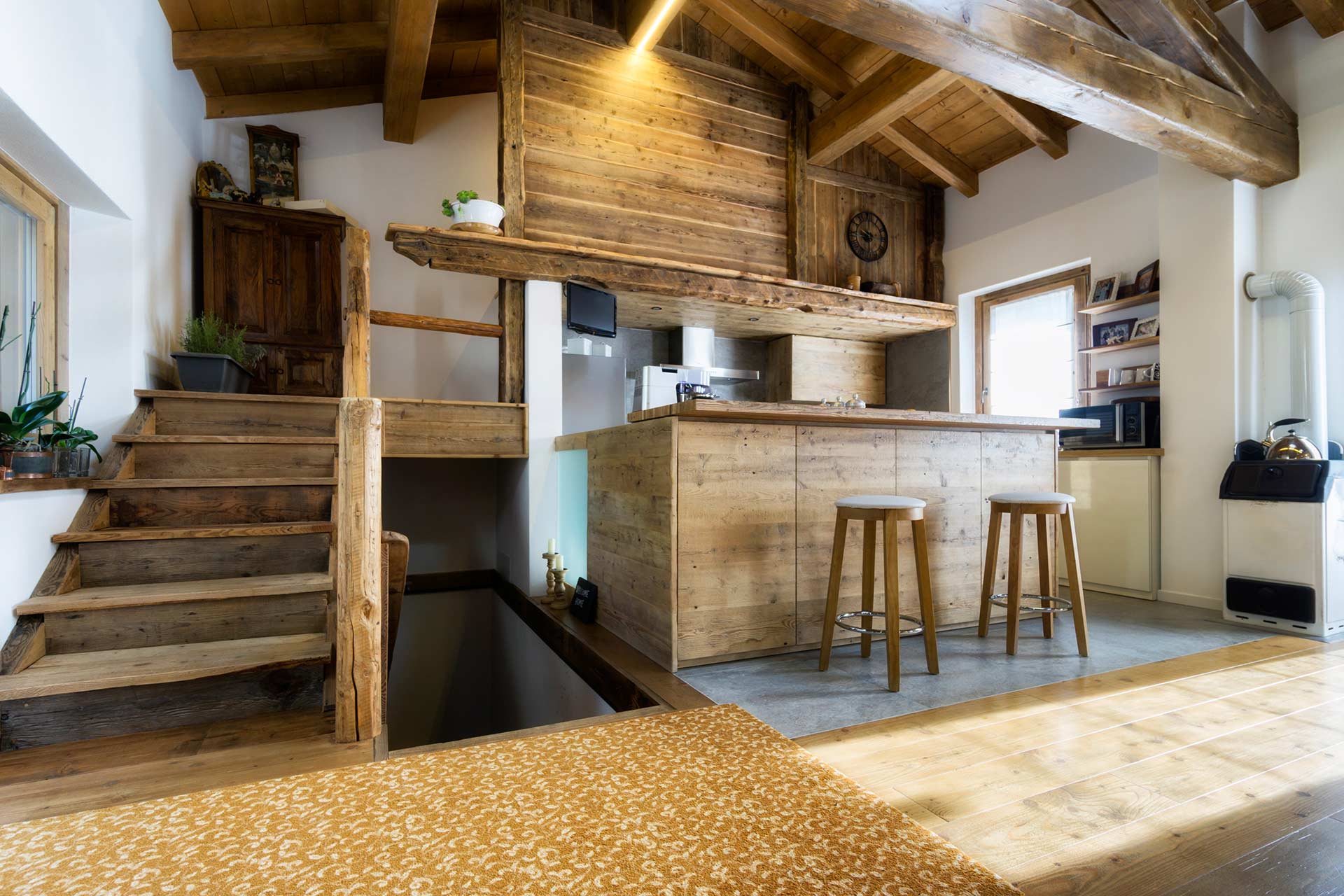 Innenraum mit Holztreppe, Holzboden und Küche aus massivem Holz in rustikalem Design